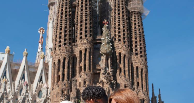 Un couple souriant pose pour un selfie devant les tours majestueuses de la Sagrada Família