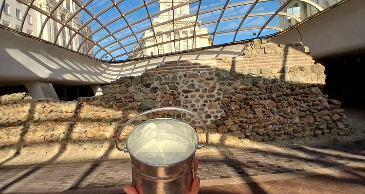 Seau de yaourt tenu à l'intérieur des ruines de Serdica au toit en verre avec un bâtiment gouvernemental en arrière-plan