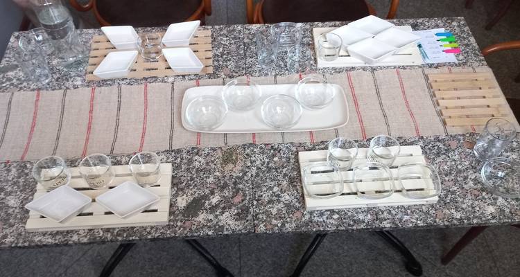 Une table en granit intérieur joliment dressée avec des verres de dégustation, de petites assiettes et un chemin de table rustique, prête pour un atelier culinaire.