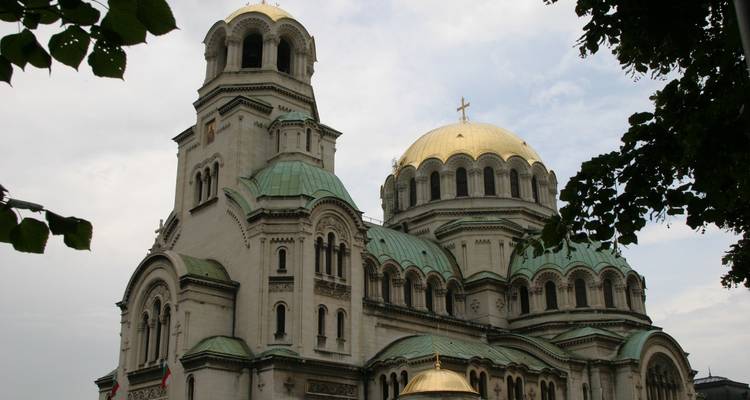 Vue latérale des dômes de la cathédrale Alexandre Nevski encadrés par des feuilles vertes