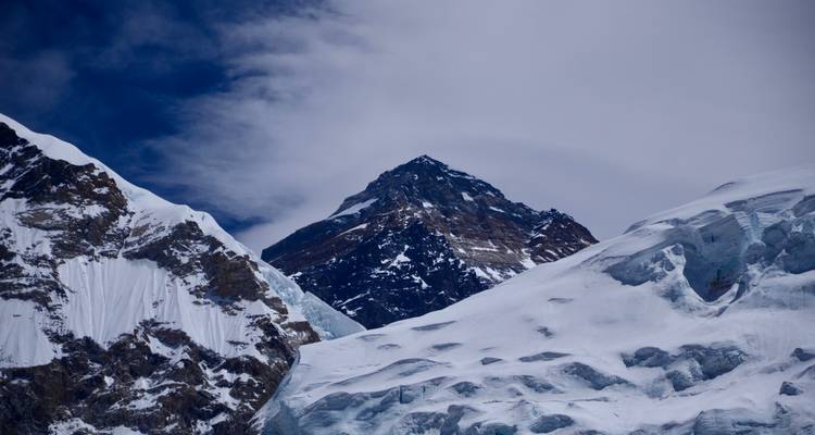 Nahaufnahme des Mount-Everest-Gipfels, umrahmt von vereisten Graten unter dramatischem Himmel.