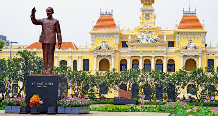 Ayuntamiento de color amarillo brillante de estilo francés-colonial con estatua de Ho Chi Minh y jardines bien cuidados en la Ciudad de Ho Chi Minh.