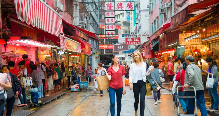 Crowded street market in Hong Kong with colourful signs and shoppers in rainy weather