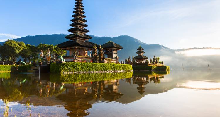 Complejo del templo Ulun Danu Beratan reflejado en un tranquilo lago de montaña al amanecer en Bali.