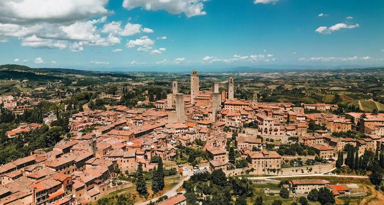Drone view of San Gimignano’s medieval stone towers rising above the Tuscan countryside.