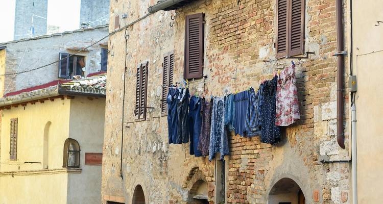 Rustic brick house with shutters and colorful clothes hanging on a line across the windows.