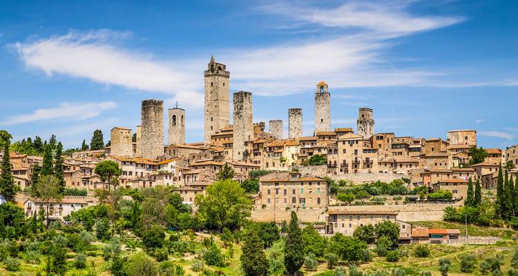 Panoramic view of San Gimignano’s medieval stone towers rising above a terracotta-roofed village and green hills.