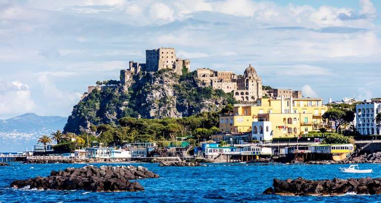 Die Aragonesische Burg erhebt sich auf einem felsigen Eiland, das mit Ischia verbunden ist und von türkisfarbenem Meer und farbenfrohen Häusern umrahmt wird.