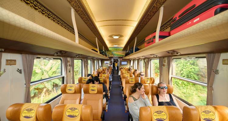 Passagiers ontspannen zich in een moderne, comfortabel ingerichte treinwagon met grote ramen.