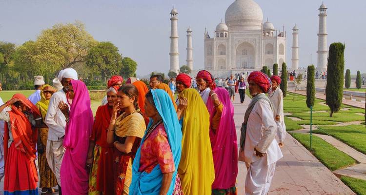 Kleurig geklede bezoekers voor het marmeren mausoleum van de Taj Mahal.