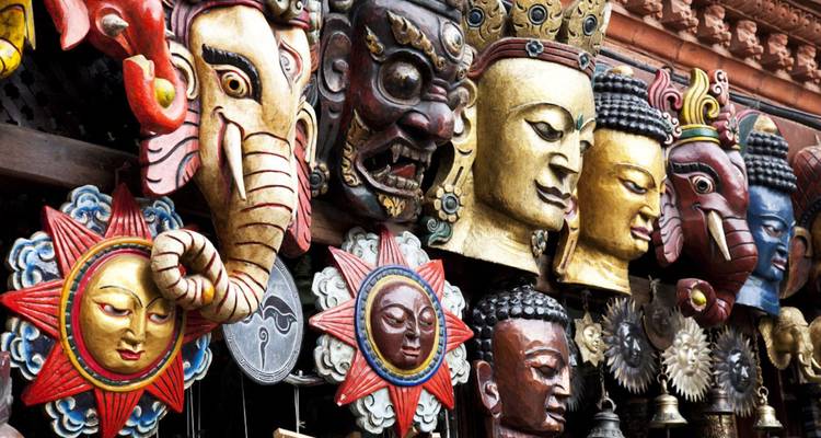 Rij met fel gekleurde Nepalese rituele maskers en snijwerk uitgestald op een marktkaraampje.