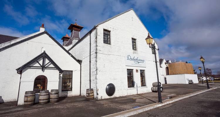 Bâtiment de la distillerie Dalwhinnie blanchi à la chaux avec enseigne sous un ciel bleu