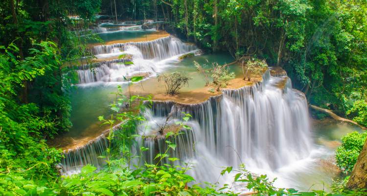 Multi-tiered tropical waterfall cascading through dense green jungle foliage