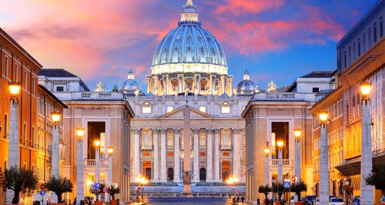 Twilight uitzicht naar beneden Via della Conciliazione naar de Sint-Pieterbasiliek onder een levendige roze-oranje lucht.
