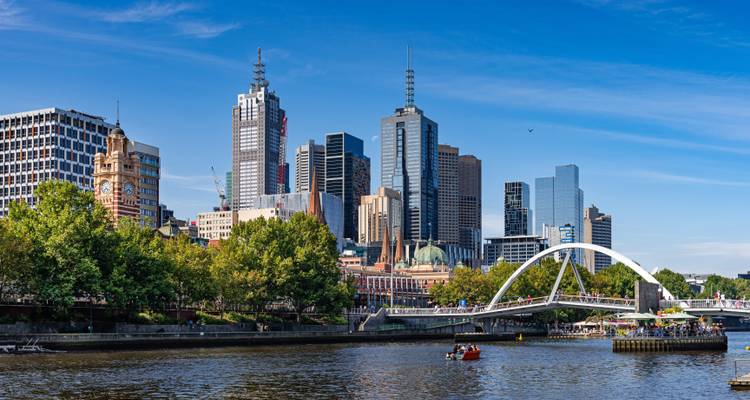 Modern skyline of Melbourne with arch footbridge spanning the Yarra River on a clear day.