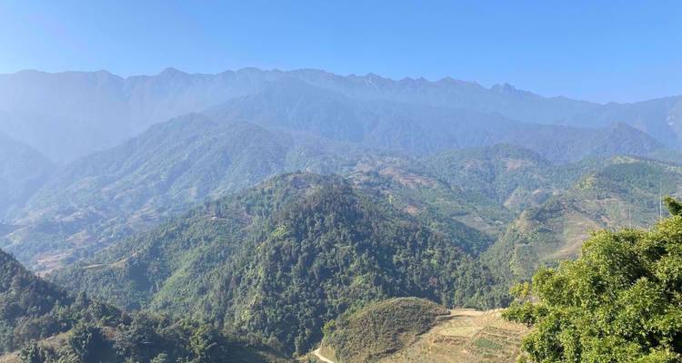 Panoramablick auf neblige, bewaldete Berge und Täler in Nordvietnam unter klarem blauen Himmel