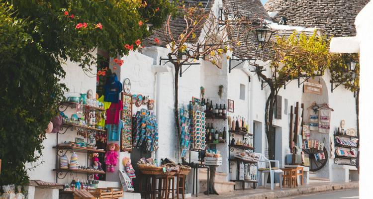 Charmante Straße mit Souvenirständen und weißen Trulli-Häusern unter strahlender Sonne