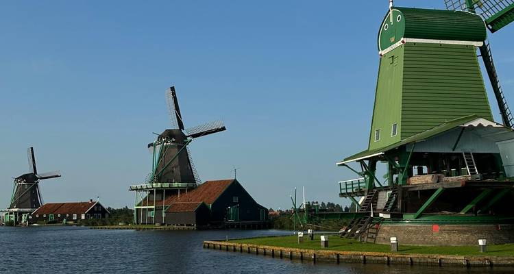 Les moulins à vent verts traditionnels se dressent au bord d'une eau calme sous un ciel bleu clair aux Pays-Bas.