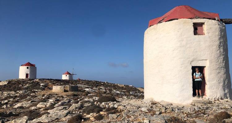 Los antiguos molinos blancos con techos rojos se alzan en una colina rocosa bajo cielos azules y despejados.