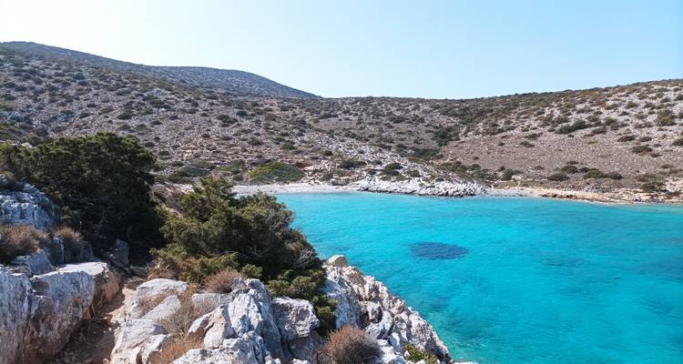 Bahía turquesa y apartada rodeada de escarpadas formaciones calcáreas y arbustos dispersos en la isla de Iraklia.