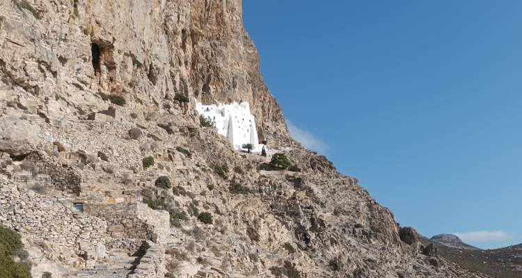 El Monasterio de Hozoviotissa, blanqueado, se aferrra dramáticamente a un acantilado imponente bajo un cielo azul profundo.