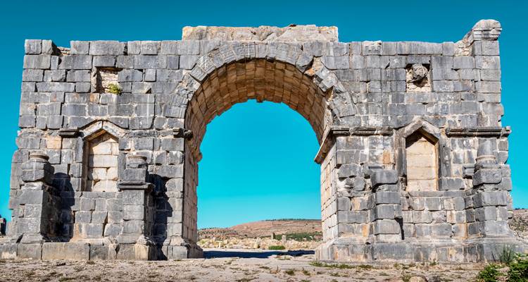 Goed bewaarde triomfboog van de oude Romeinse stad Volubilis tegen een heldere blauwe lucht.