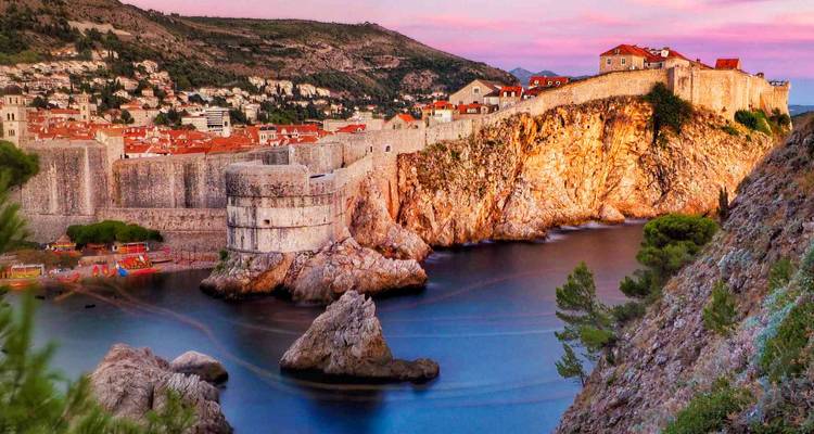 Vue du coucher de soleil sur les remparts fortifiés de Dubrovnik et les toits en terre cuite illuminés au-dessus de la mer Adriatique.
