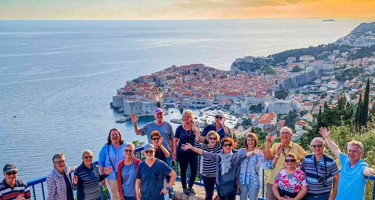 Groupe de touristes joyeux posant sur un point de vue dominant Dubrovnik et la mer scintillante.
