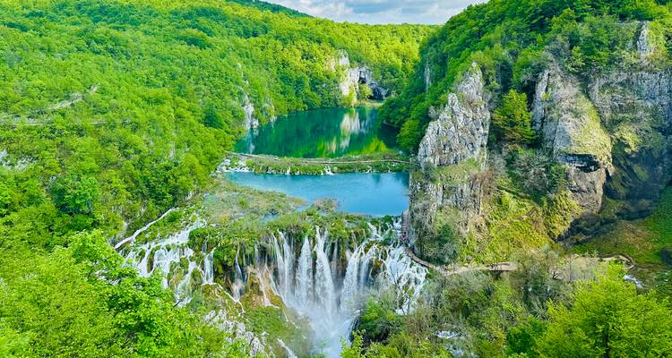 Des cascades luxuriantes en étages se déversant dans des lacs d'un bleu turquoise éclatant entourés d'une forêt dense et verdoyante.