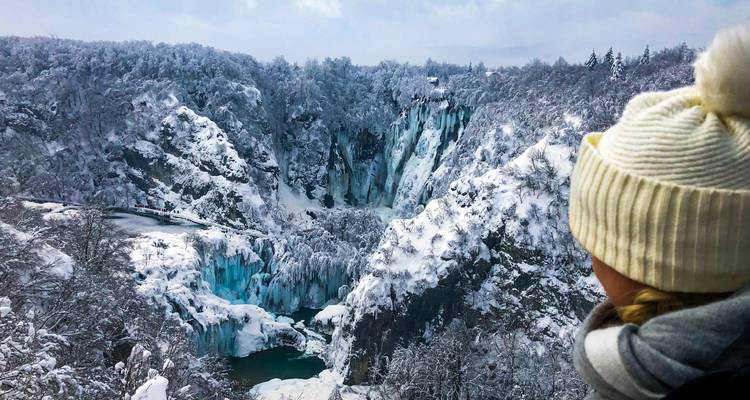 Le voyageur contemple les cascades et les falaises recouvertes de neige aux lacs de Plitvice.