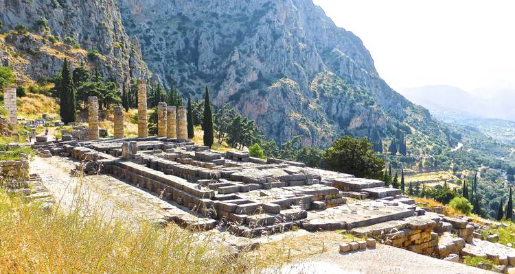 Les ruines de pierre anciennes d'un complexe de temples situé sur le flanc d'une montagne avec des falaises spectaculaires en arrière-plan