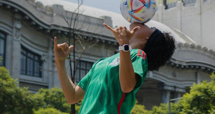 Un artiste de rue équilibrant un ballon de football sur son front devant un bâtiment historique orné