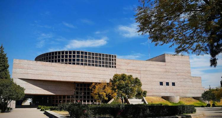 Bâtiment de musée en pierre et verre moderne se détachant sur un ciel bleu dégagé