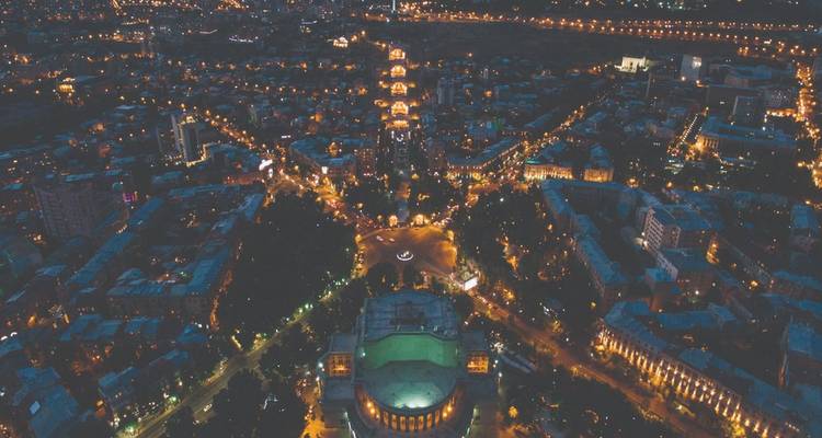 Vue aérienne nocturne de la ville d'Erevan avec des rues illuminées rayonnant de l'opéra.