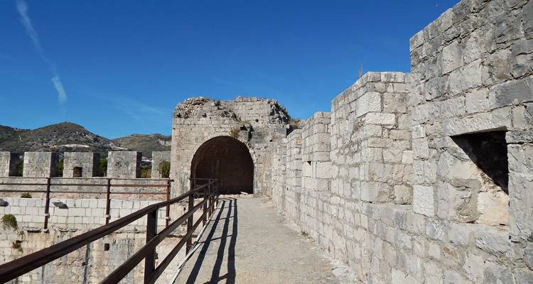 Murs de pierre et arche d'une forteresse de montagne contre un ciel dégagé