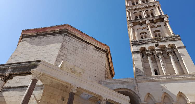 Vista hacia arriba de la torre campanario de la Catedral de Split y muros antiguos adyacentes contra un cielo despejado