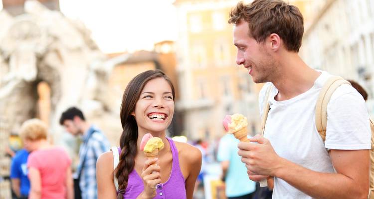 Couple souriant savourant des cornets de gelato sur une piazza romaine animée
