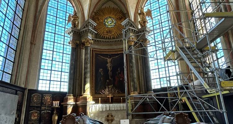 Interior de iglesia histórica con vidrieras de colores, altar y andamios temporales para la restauración.