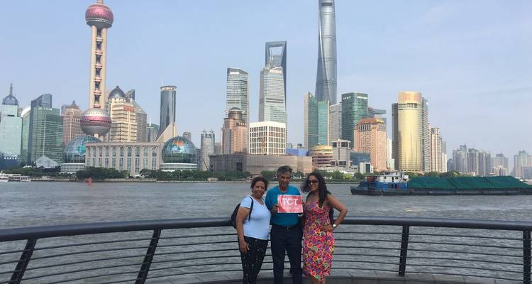 Trois voyageurs se tiennent sur le Bund avec l'emblématique skyline de Shanghai, incluant la Tour de la Perle Orientale et la Shanghai Tower, qui s'élèvent derrière eux.