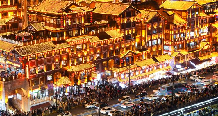 Panorama nocturne des bâtiments riverains de style Hongyadong de Chongqing brillant de lumières dorées et de la circulation routière animée en dessous.