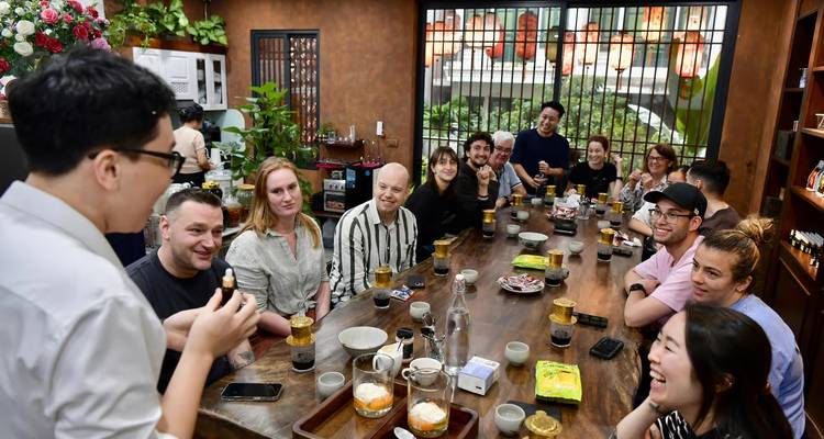 Grupo animado de viajeros probando café con huevo vietnamita y riendo alrededor de una mesa larga