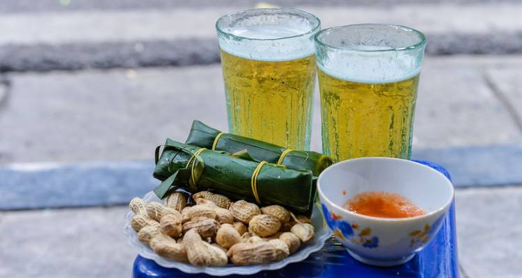 Plato de botanas callejeras con cacahuates, galletas de arroz, salsa para acompañar y dos vasos de cerveza