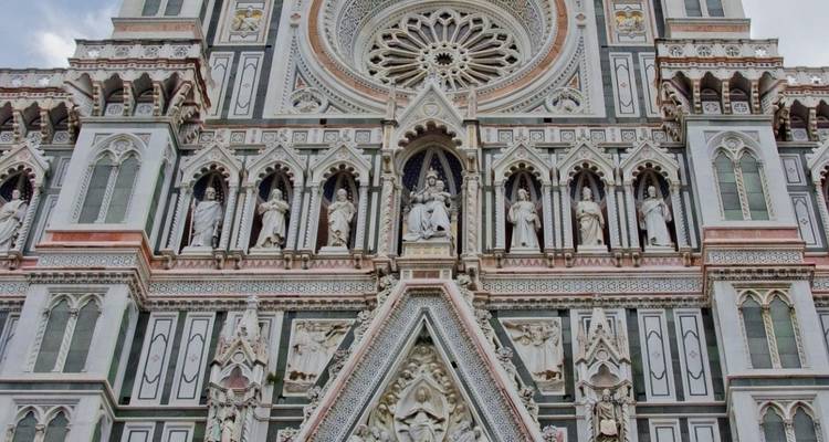 Fachada de mármol detallada de la Catedral de Florencia mostrando estatuas, rosetón e intrincados patrones verde y blanco.