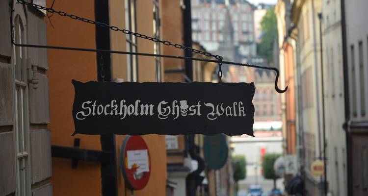 Cartel colgante que dice "Stockholm Ghost Walk" en un estrecho callejón empedrado en Gamla Stan.