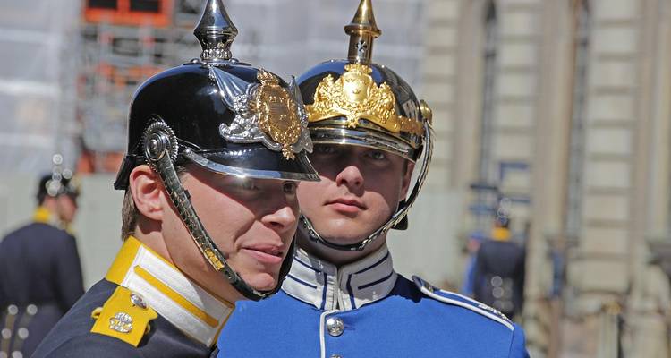 Primer plano de guardias reales uniformados usando cascos ornamentados durante un acto ceremonial.