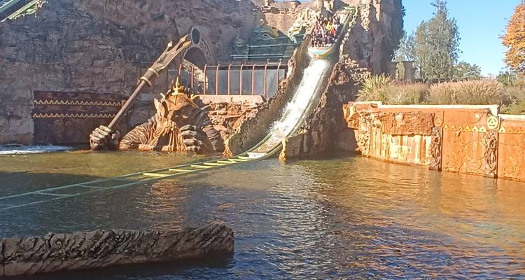 Paseo en tronco acuático que se desliza rápidamente por una rampa temática hacia una piscina de salpicaduras en un parque de diversiones