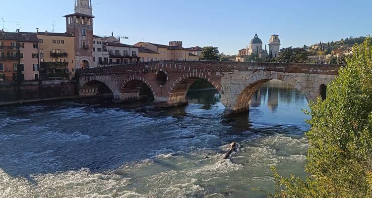 Arcos de piedra del Ponte Pietra cruzando el río Adige de rápido flujo en Verona