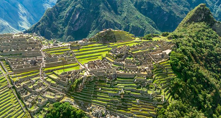 Luftaufnahme der terrassierten Ruinen von Machu Picchu, umgeben von üppigen Anden-Bergen.