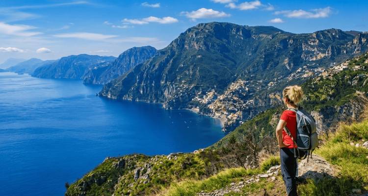 Un randonneur contemple les falaises spectaculaires de la côte amalfitaine qui plongent dans une mer bleu profond