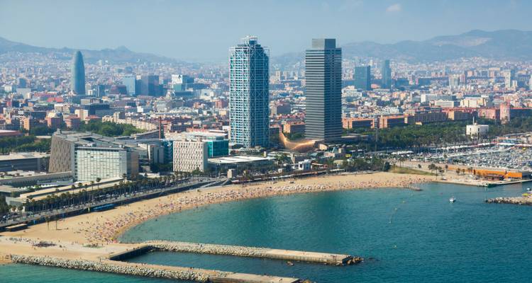 Vue aérienne de la plage urbaine de Barcelone avec une eau turquoise, des gratte-ciel côtiers jumeaux et des collines lointaines